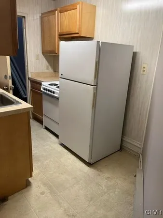 a white refrigerator freezer and a stove sitting inside of a kitchen