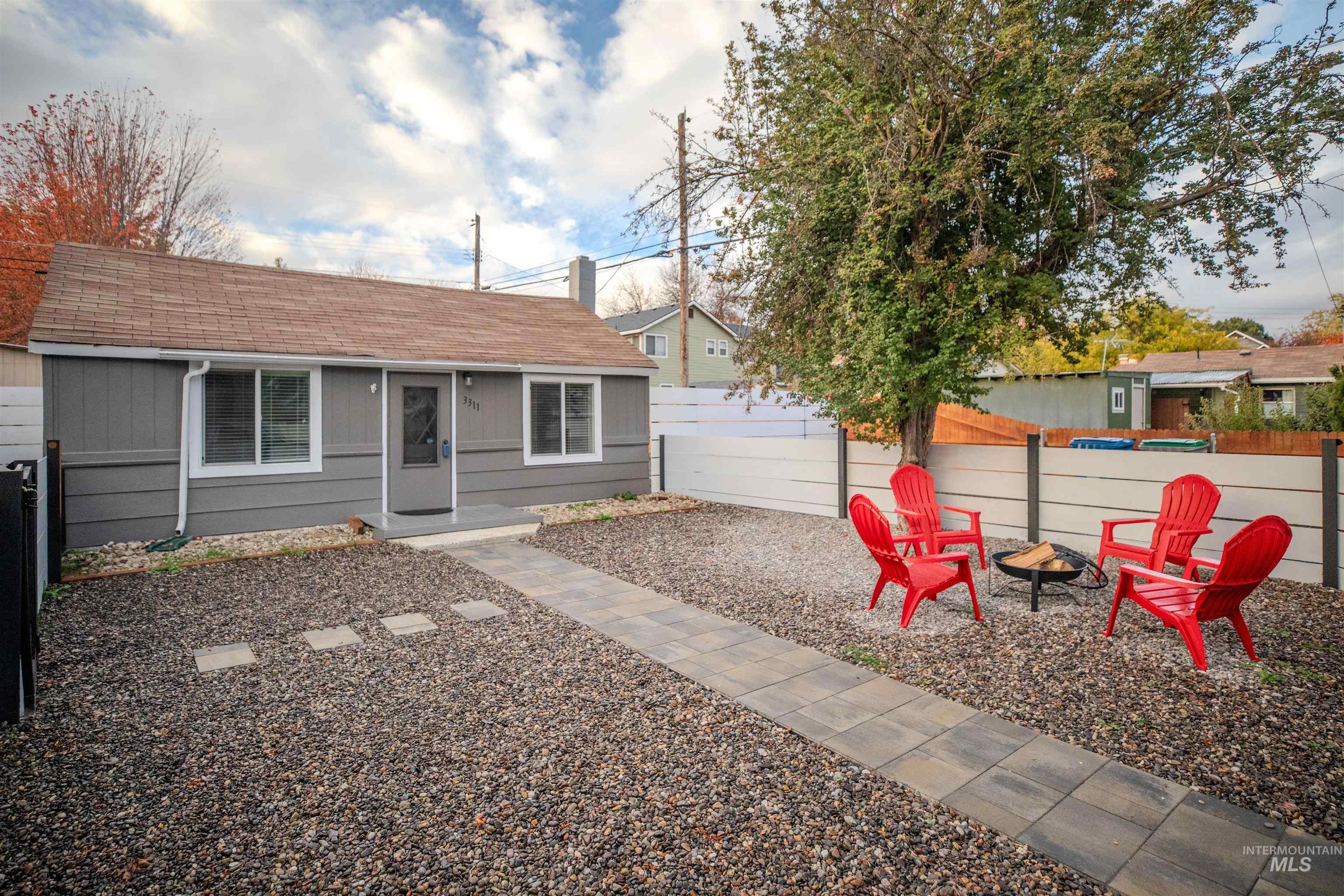 View of front of property with a fire pit, roof with shingles, and a fenced front yard