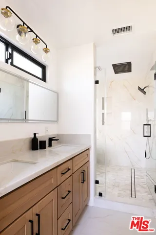 a bathroom with a double vanity sink a mirror and shower