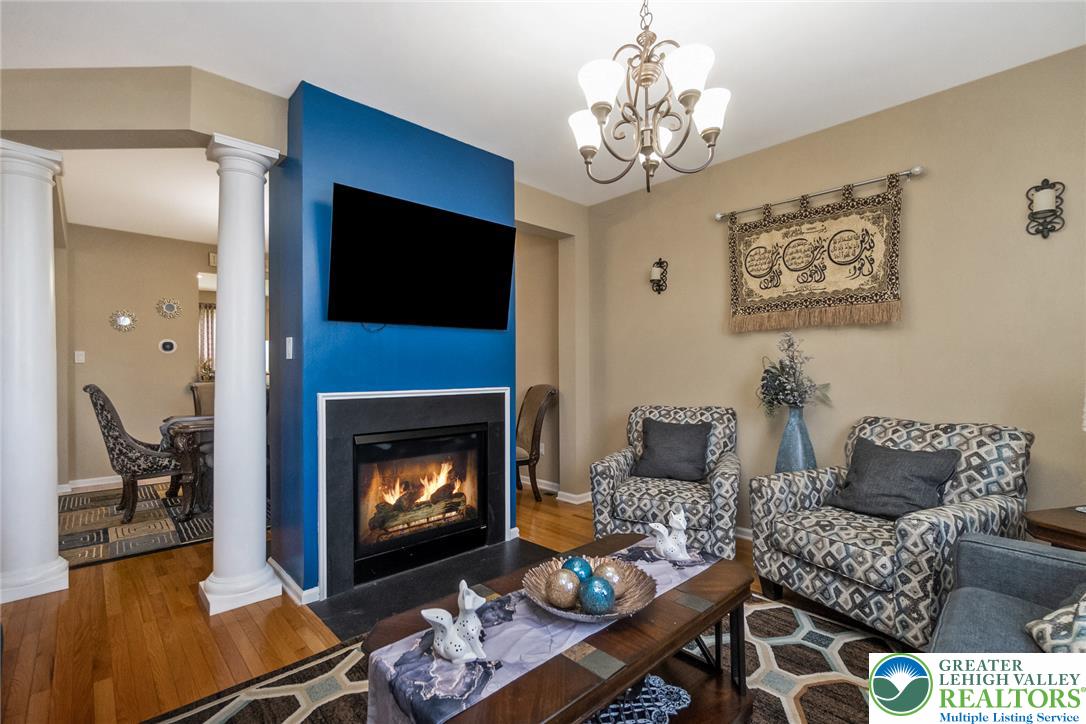3566 Penfield Way Nazareth, PA 18064 - Photo 20 of 47 A welcoming living area boasts a cozy fireplace, lustrous hardwood flooring, and an elegant chandelier.