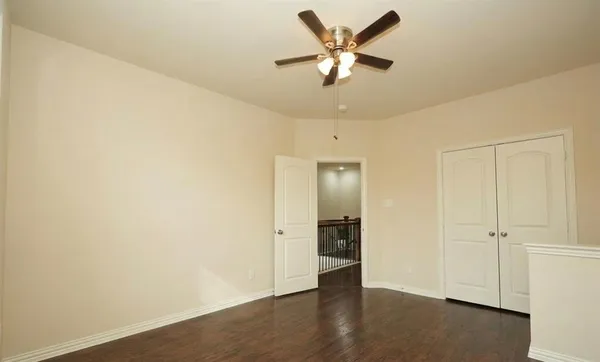 an empty room with wooden floor and a ceiling fan