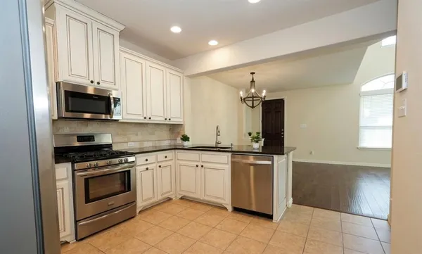a kitchen with stainless steel appliances granite countertop a stove a sink and a microwave