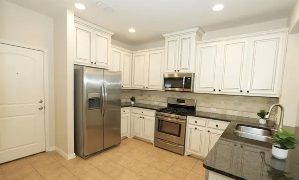 a kitchen with stainless steel appliances granite countertop a refrigerator sink and stove