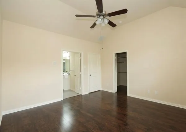 an empty room with wooden floor fan and windows