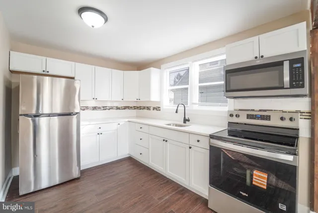 a kitchen with cabinets stainless steel appliances and wooden floor