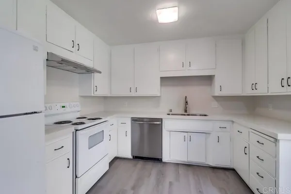 a kitchen with cabinets stainless steel appliances and wooden floor