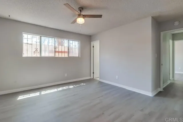 an empty room with wooden floor fan and windows