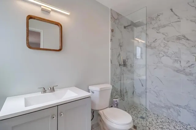 a bathroom with a toilet sink vanity and shower