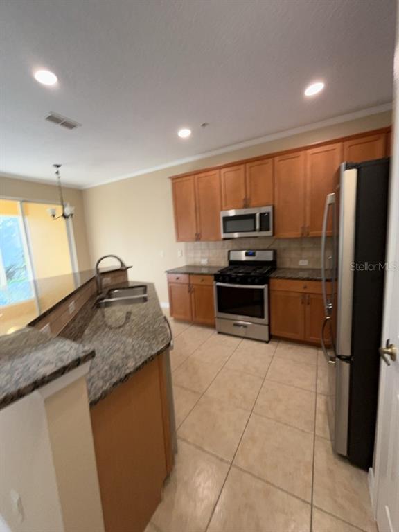 839 Assembly Court Reunion, FL 34747 - Photo 3 of 16 a kitchen with stainless steel appliances granite countertop a sink stove and refrigerator