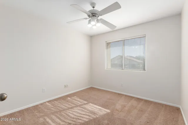 an empty room with a chandelier fan and windows