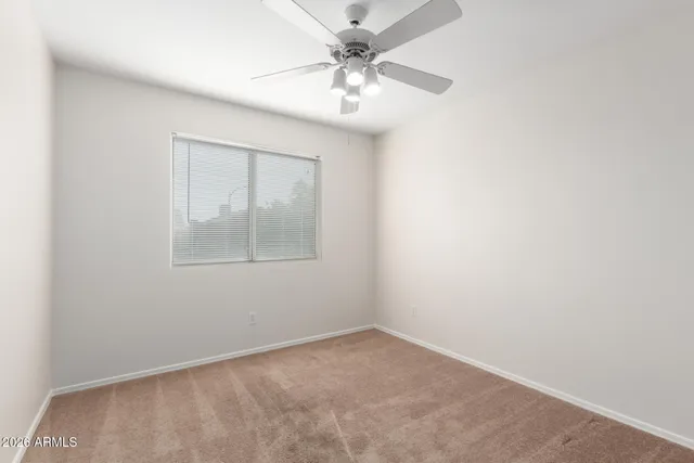 an empty room with a window and a fan