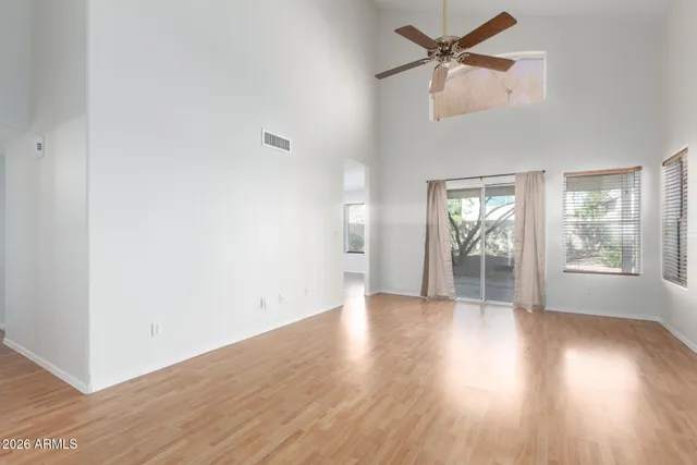 an empty room with wooden floor fan and windows