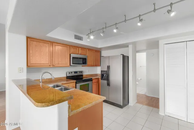 a kitchen with stainless steel appliances granite countertop a sink stove refrigerator and cabinets