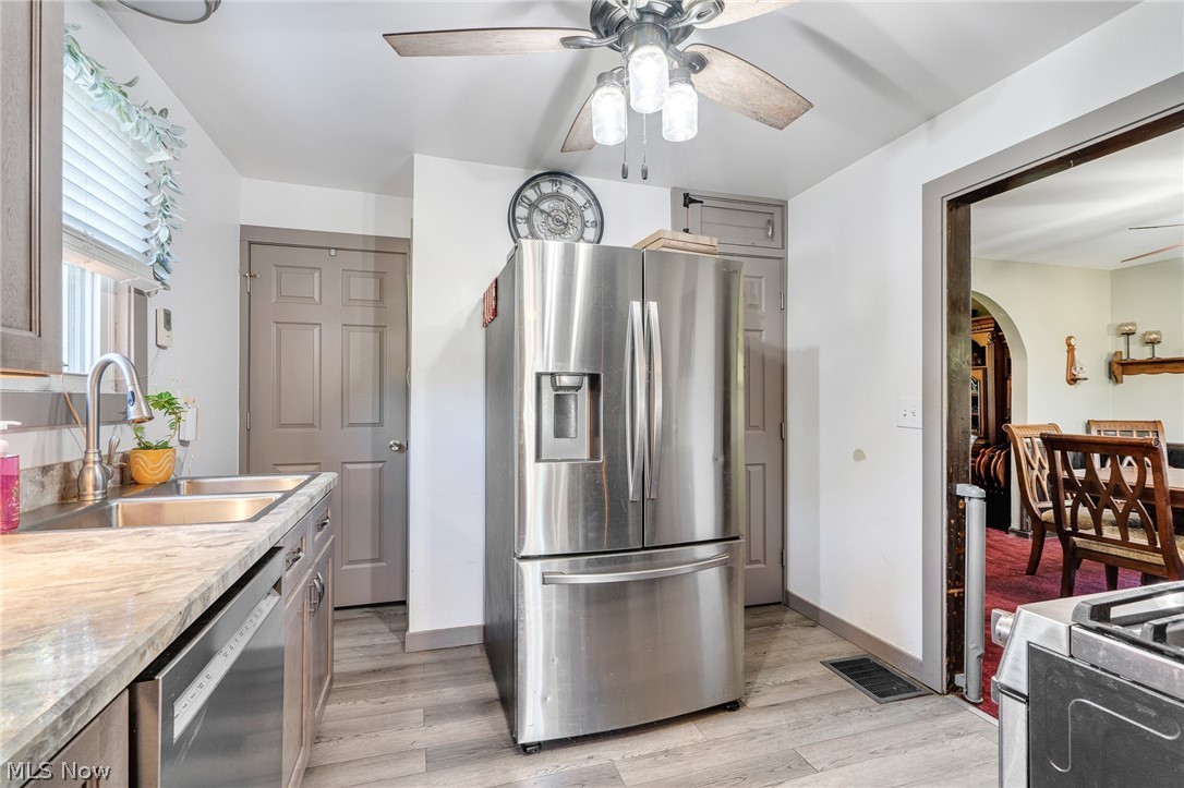 5840 Poland Struthers Road Youngstown, OH 44514 - Photo 25 of 50 Stainless steel French door refrigerator, dual basin sink with pull-down faucet, wood-finish flooring, ceiling fan with integrated lighting, and a window with blinds