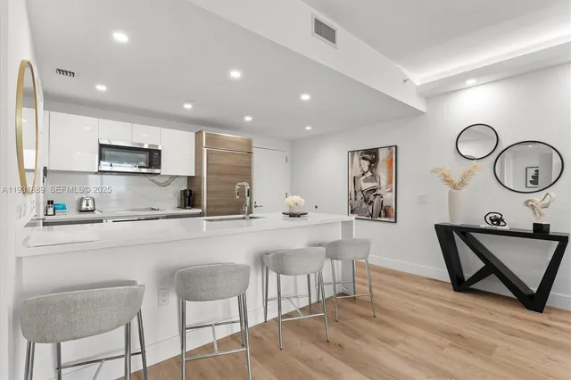 a kitchen with stainless steel appliances granite countertop a sink a stove a refrigerator cabinets and chairs