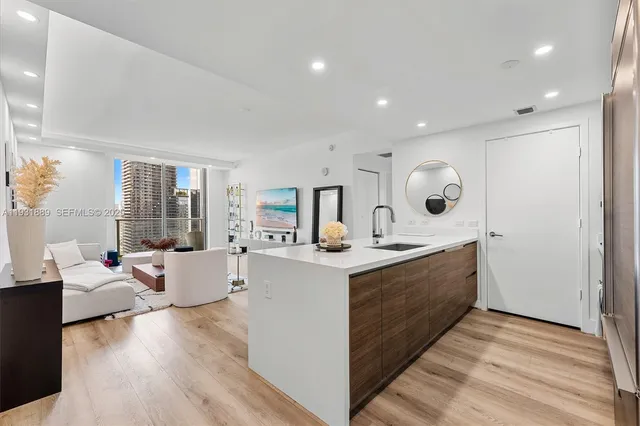 a large room with kitchen island a sink dishwasher a dining table and chairs with wooden floor