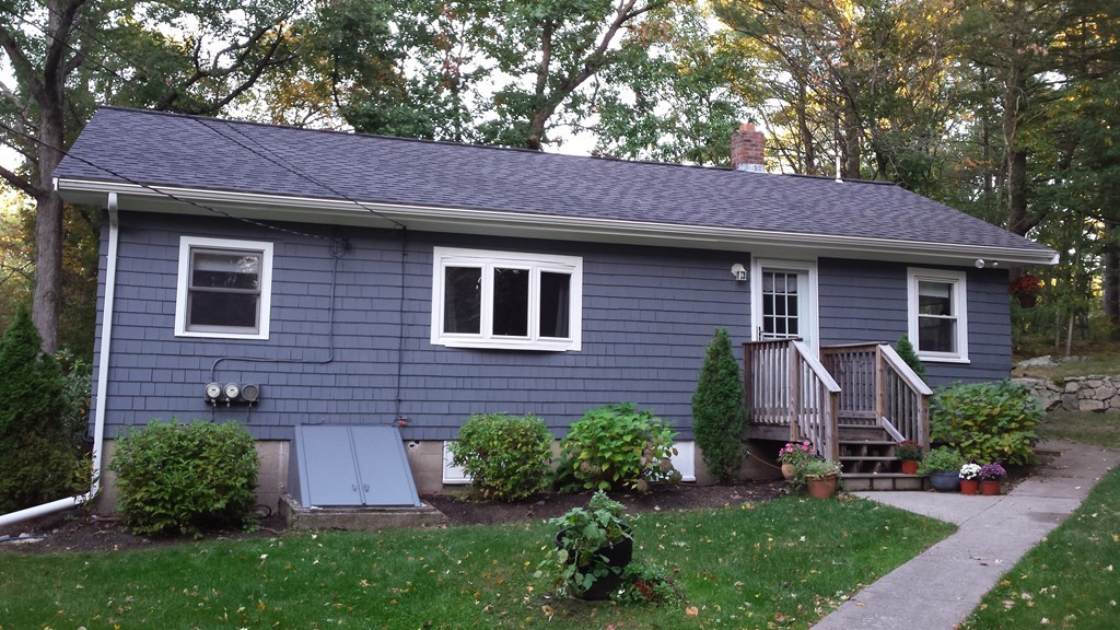 a view of a house with a yard plants and large tree