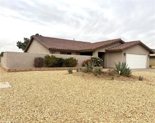 a backyard of a house with table and chairs under an umbrella