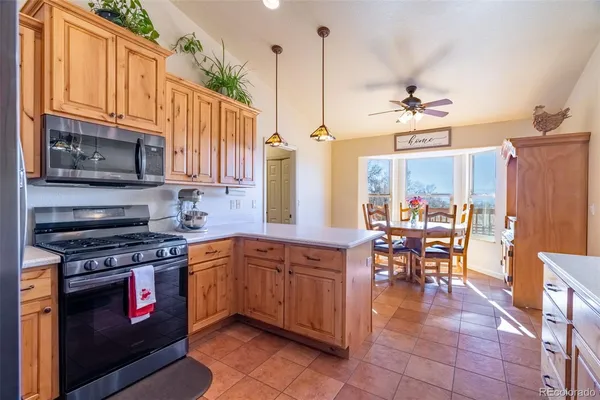 a kitchen with stainless steel appliances granite countertop a stove top oven a sink a dining table and chairs with wooden floor