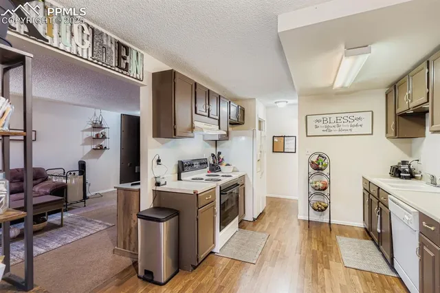 a kitchen with stainless steel appliances a stove top oven a sink a refrigerator wooden floor and cabinets