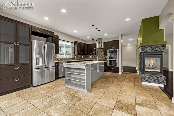 a kitchen with stainless steel appliances kitchen island granite countertop a refrigerator and a stove top oven