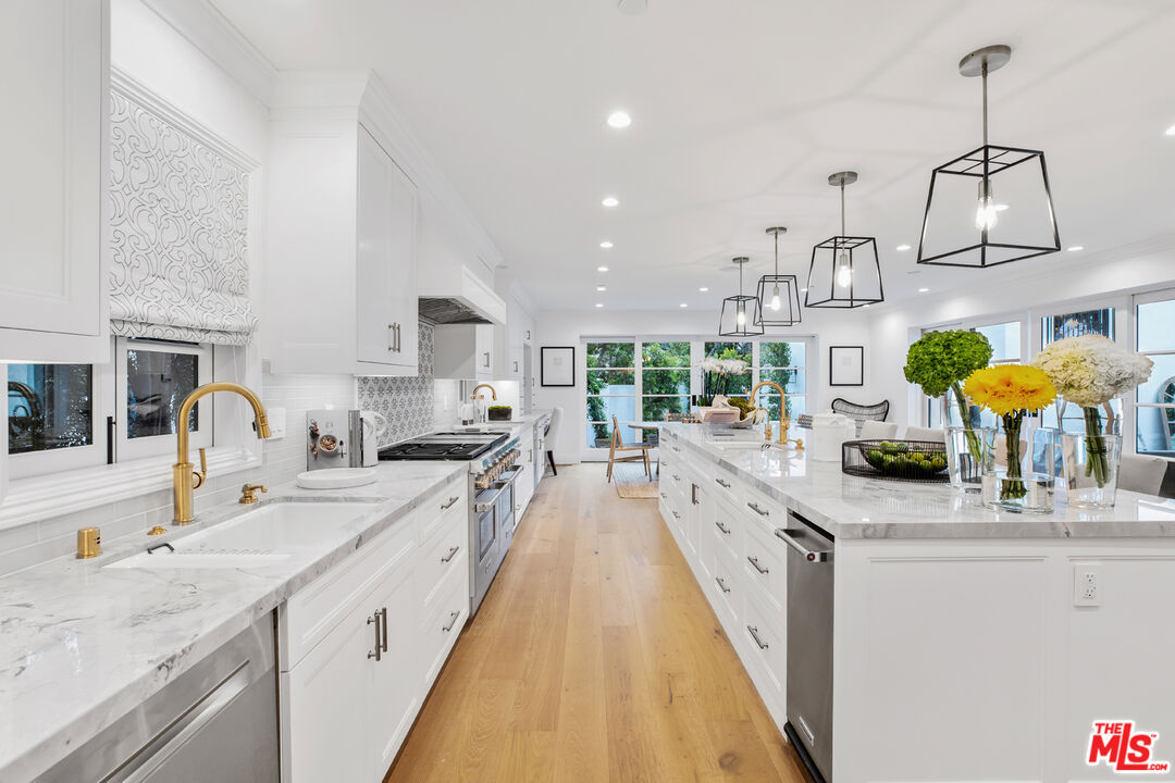 623 Walden Drive Beverly Hills, CA 90210 - Photo 7 of 28 a large kitchen with stainless steel appliances granite countertop a sink dishwasher and white cabinets with wooden floor