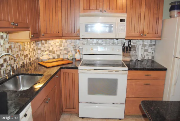 a kitchen with granite countertop a sink dishwasher stove and cabinets