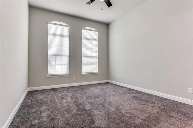 an empty room with windows and chandelier fan