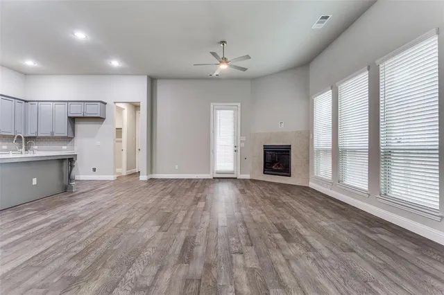 a view of a kitchen and an empty room with wooden floor and a window