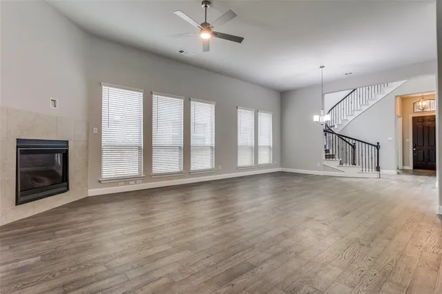 an empty room with wooden floor fireplace and windows
