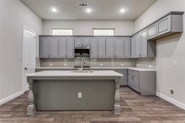 a kitchen with kitchen island granite countertop a sink cabinets and stainless steel appliances