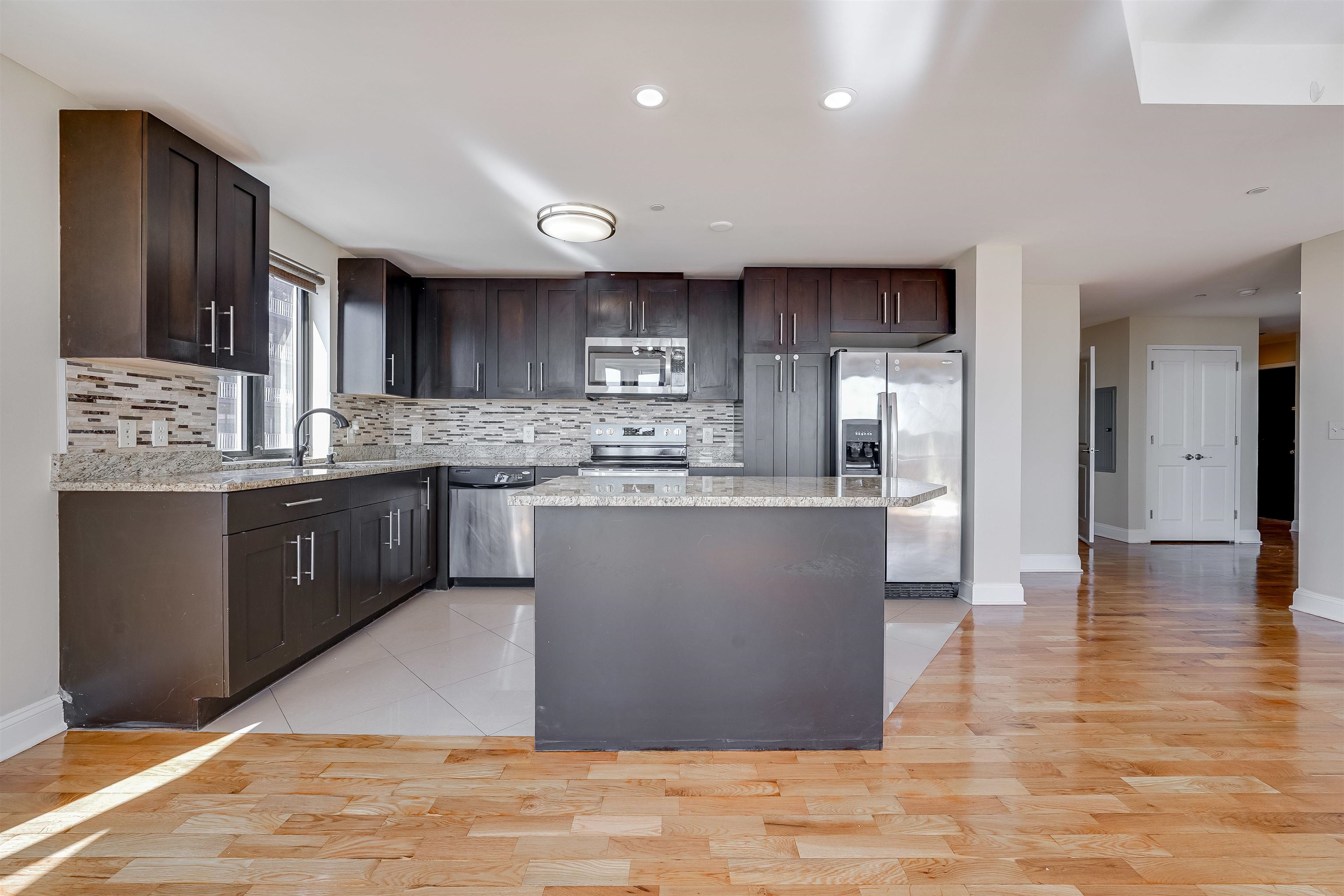 29 1st Street, Unit 401 Hackensack, NJ 07601 - Photo 6 of 23 a kitchen with stainless steel appliances granite countertop a sink counter space and cabinets