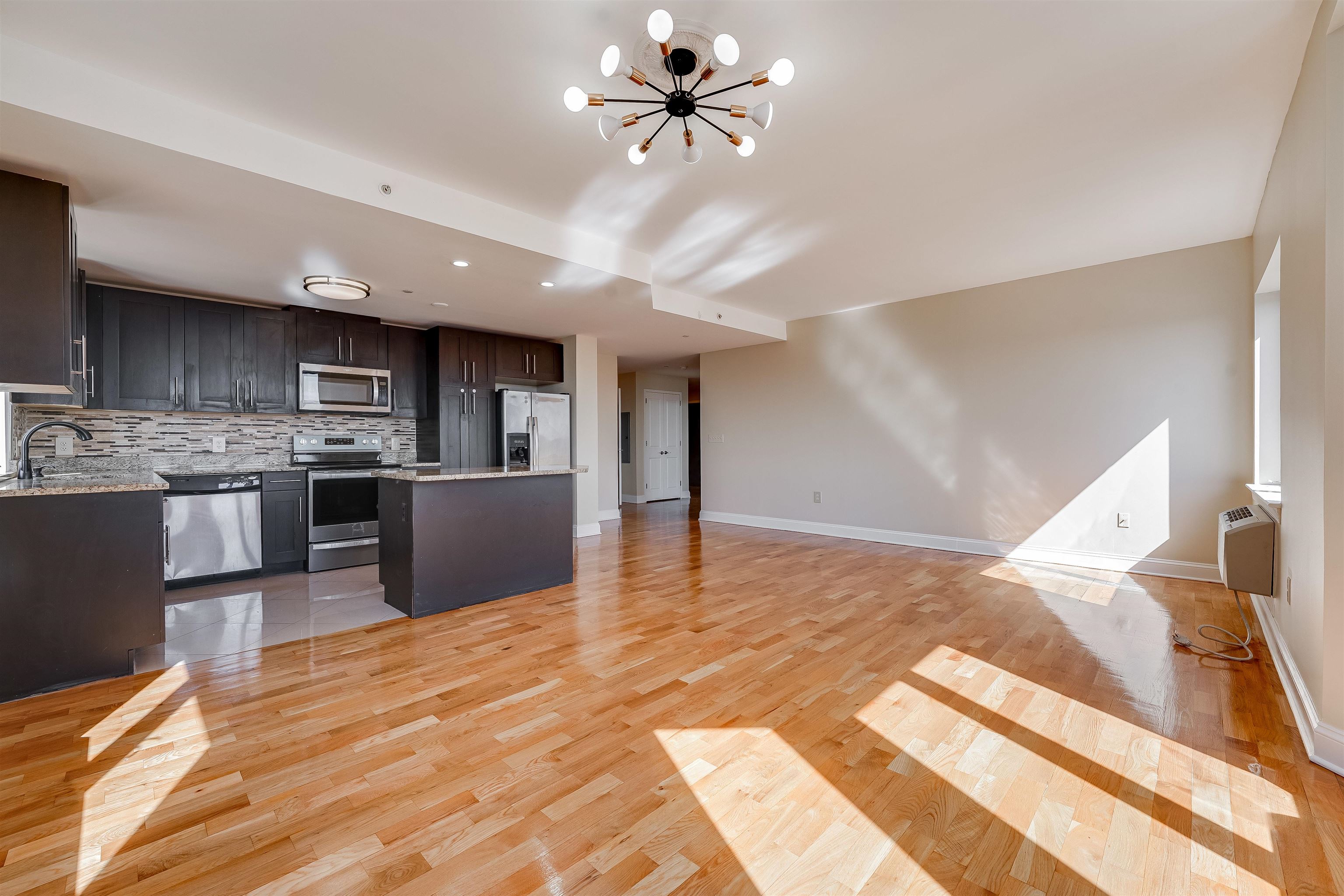 29 1st Street, Unit 401 Hackensack, NJ 07601 - Photo 7 of 23 a view of a kitchen with kitchen island a sink stainless steel appliances and cabinets