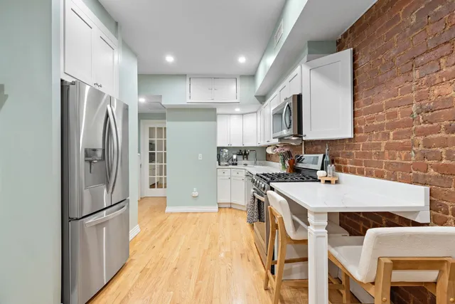 a kitchen with kitchen island a counter top space a refrigerator a sink and a stove