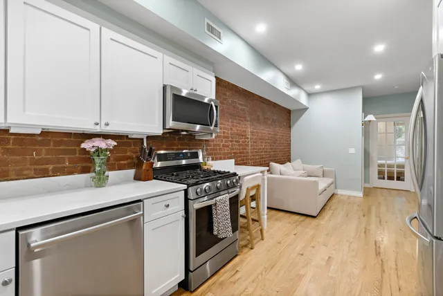 a kitchen with stainless steel appliances a stove top oven a sink dishwasher and a refrigerator with wooden floor