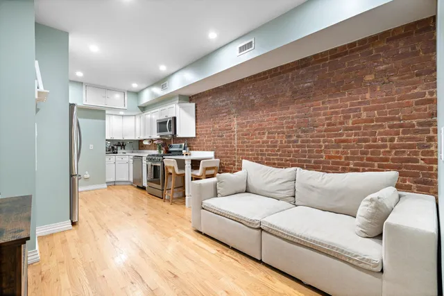 a living room with stainless steel appliances kitchen island granite countertop furniture and a couch