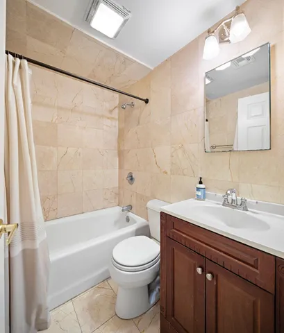 a bathroom with a bathtub shower sink vanity mirror and toilet