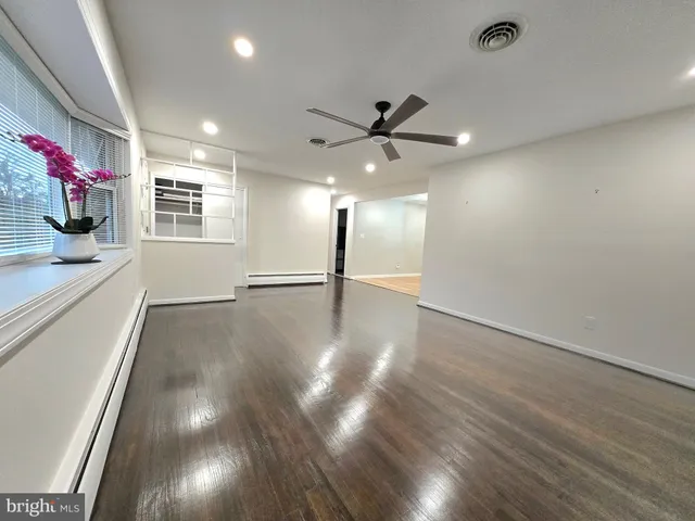 a view of an empty room with wooden floor and a window