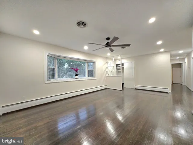 a view of an empty room with window and wooden floor