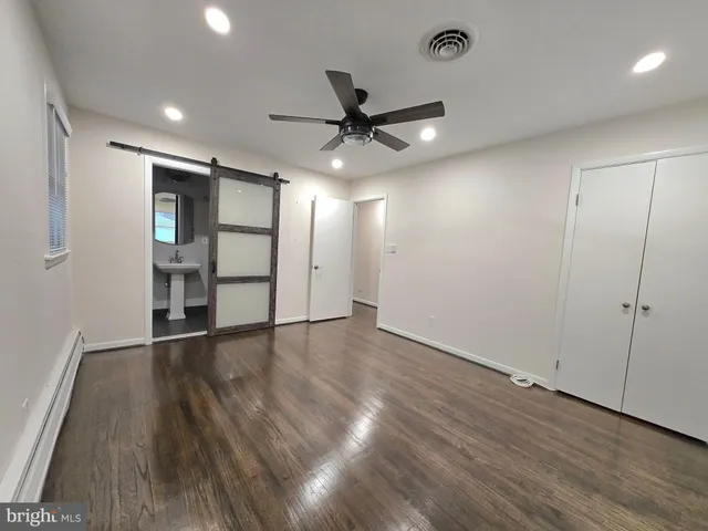 an empty room with wooden floor a ceiling fan and windows