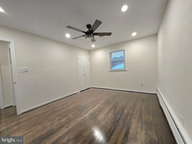 an empty room with wooden floor fan and windows