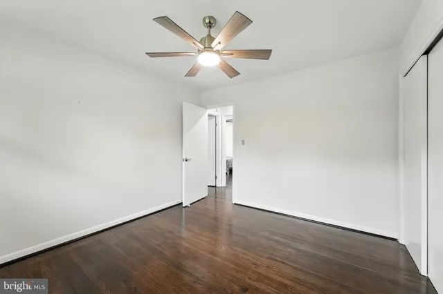 an empty room with wooden floor and ceiling fan