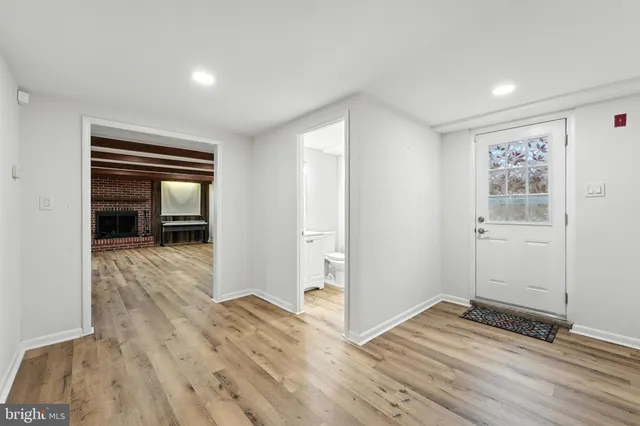 an empty room with wooden floor staircase and windows