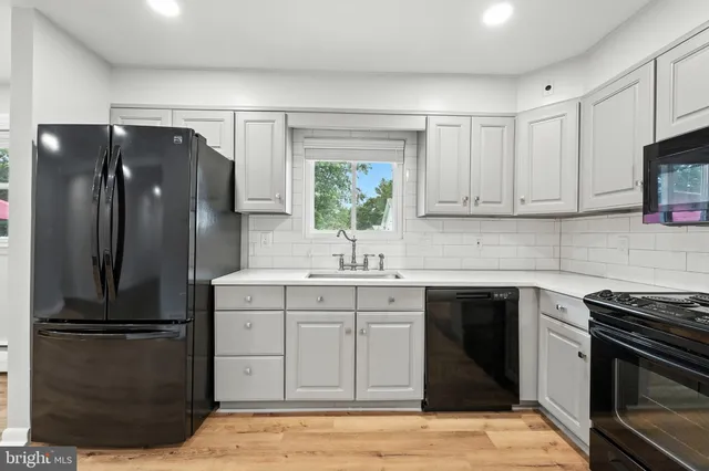 a kitchen with granite countertop a refrigerator stove and wooden floor
