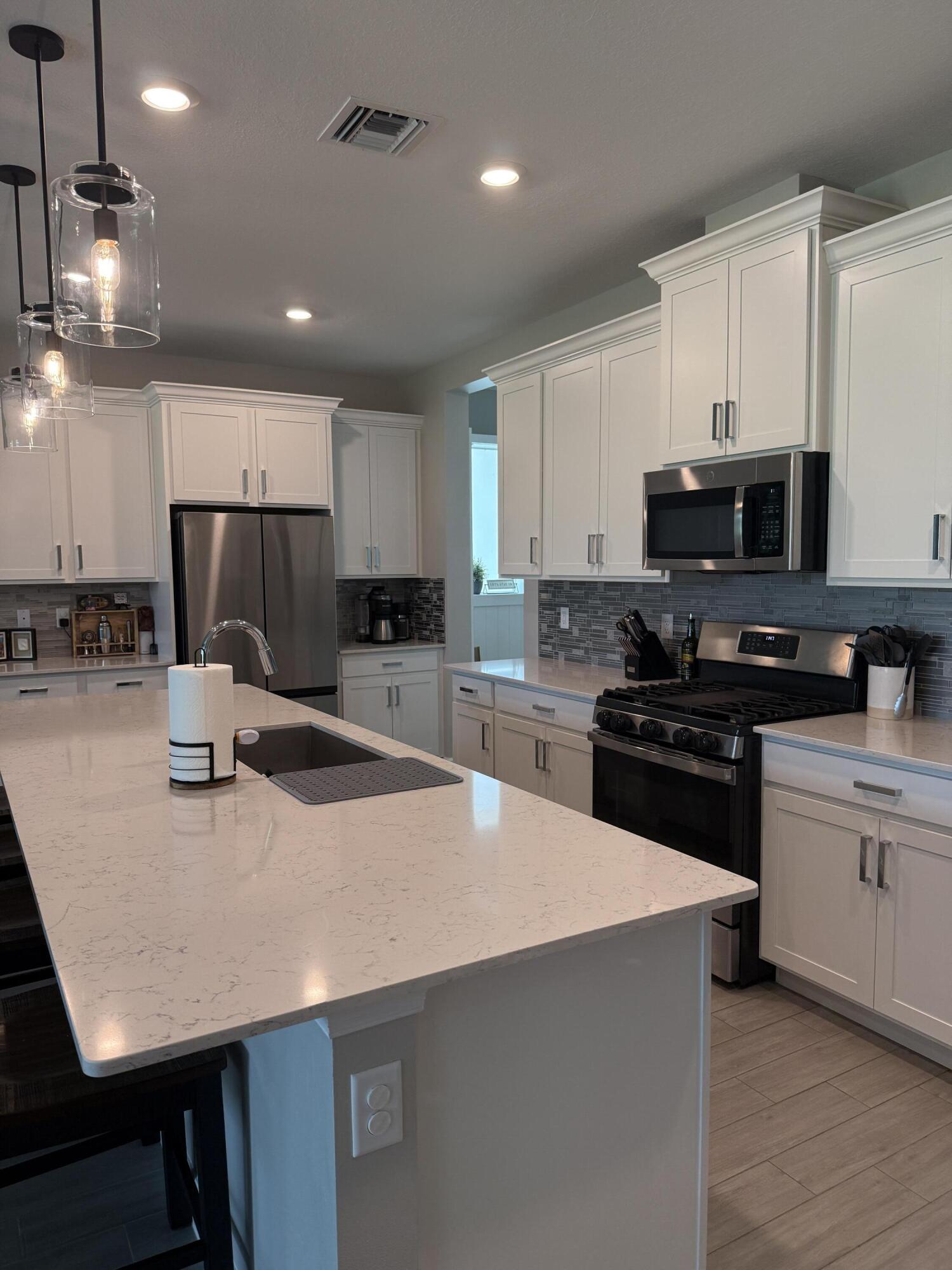 1382 Arrowhead Point Road Loxahatchee, FL 33470 - Photo 15 of 55 a kitchen with kitchen island a stove sink and cabinets
