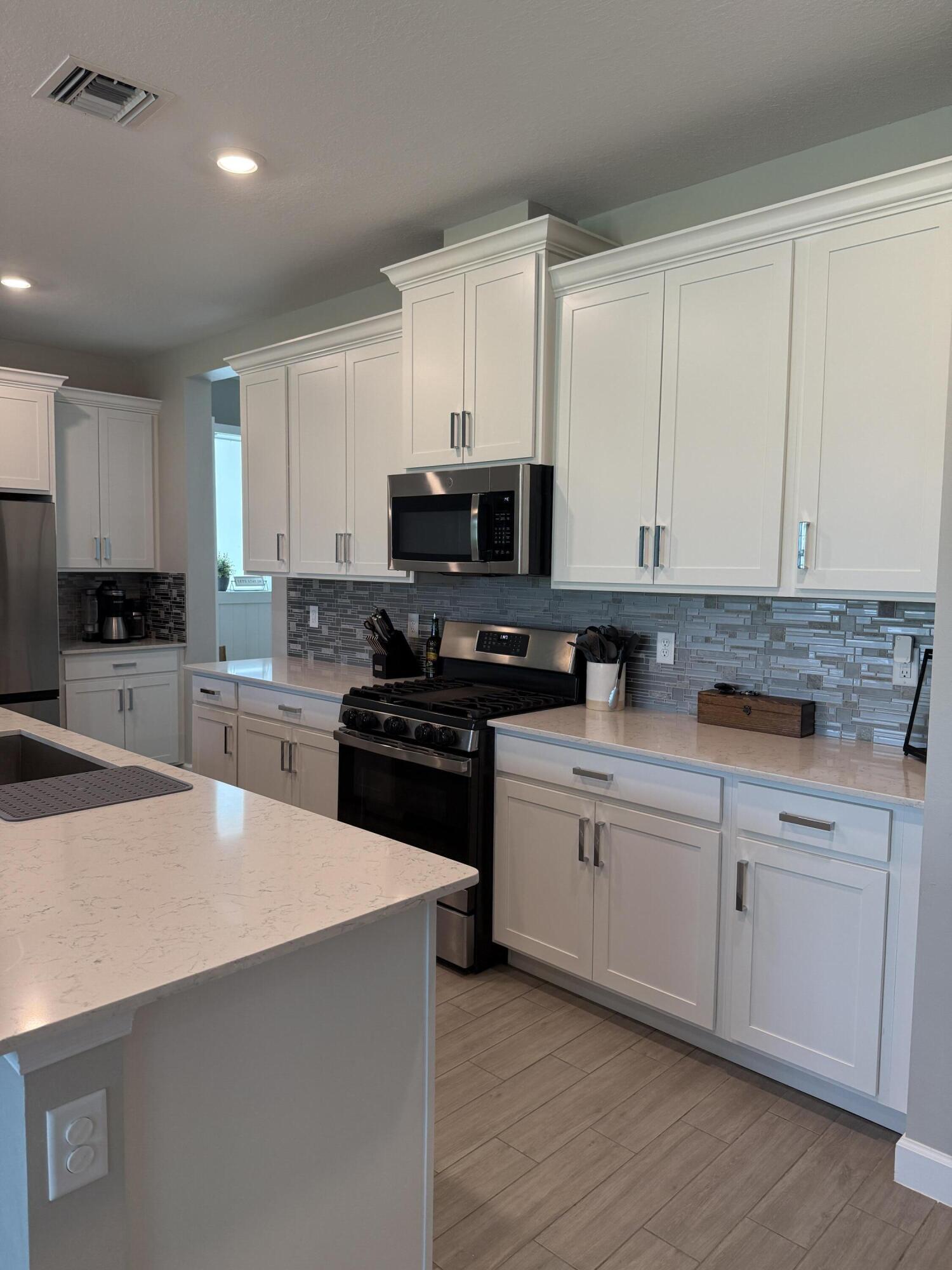 1382 Arrowhead Point Road Loxahatchee, FL 33470 - Photo 17 of 55 a kitchen with granite countertop a stove top oven a sink a counter space and cabinets
