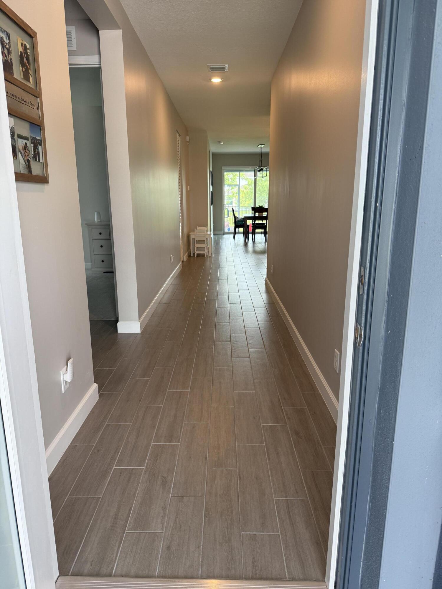 1382 Arrowhead Point Road Loxahatchee, FL 33470 - Photo 3 of 55 a hallway with wooden floor table and chairs