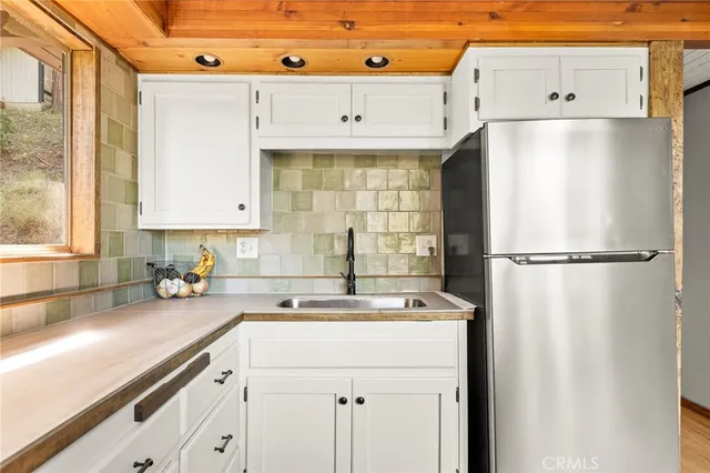 a kitchen with a sink a refrigerator and cabinets
