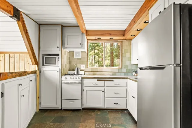 a kitchen with stainless steel appliances granite countertop a refrigerator a sink and white cabinets