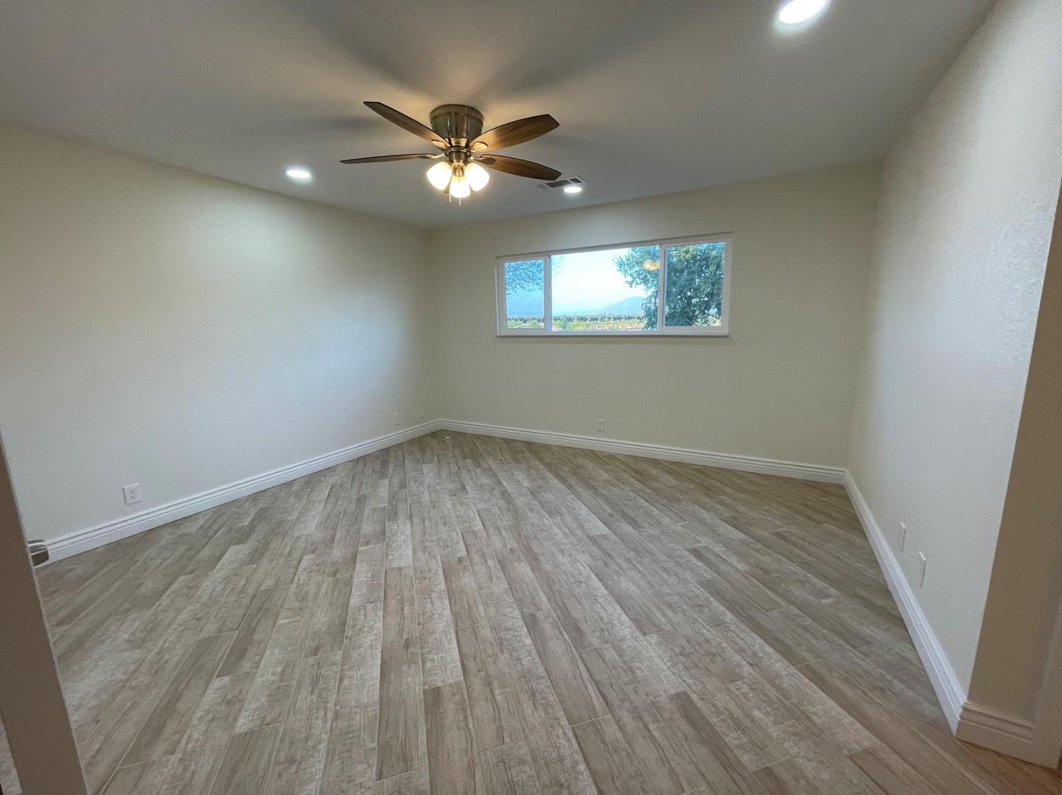 19342 East South Avenue Reedley, CA 93654 - Photo 20 of 29 an empty room with wooden floor chandelier fan and windows